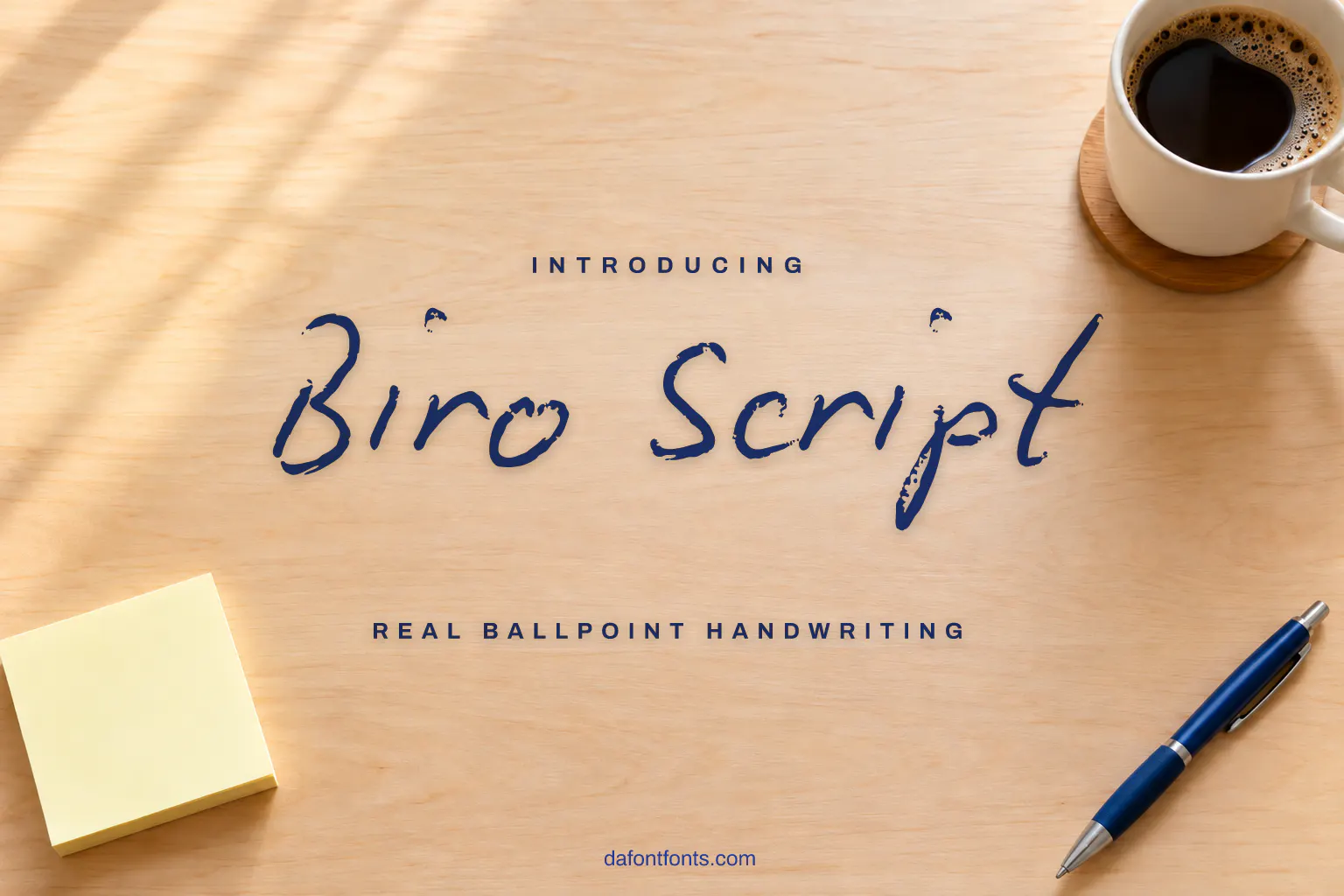 Biro Script font poster: blue ballpoint handwriting on a desk background with a pen